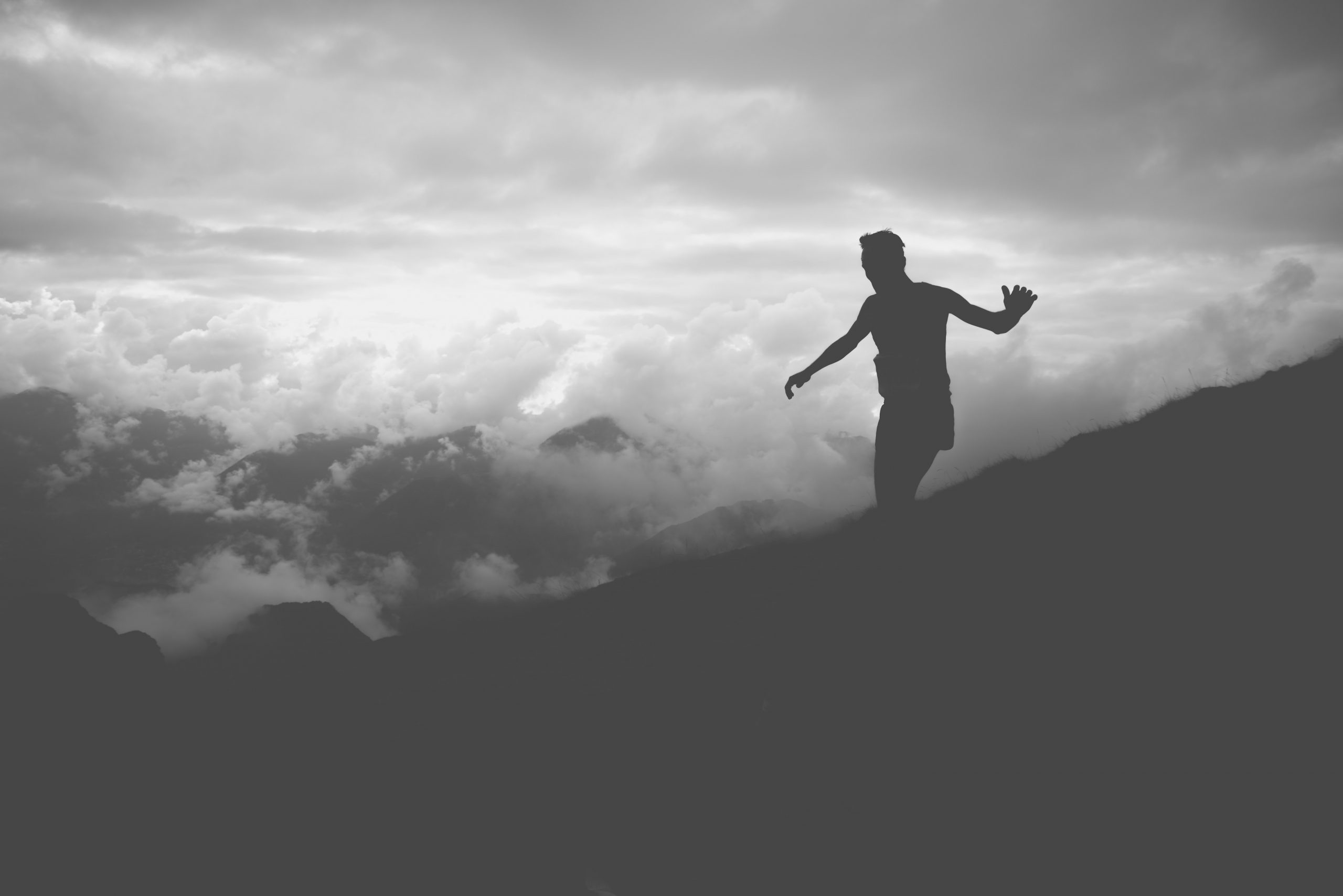 black and white photo of man running on foggy mountain